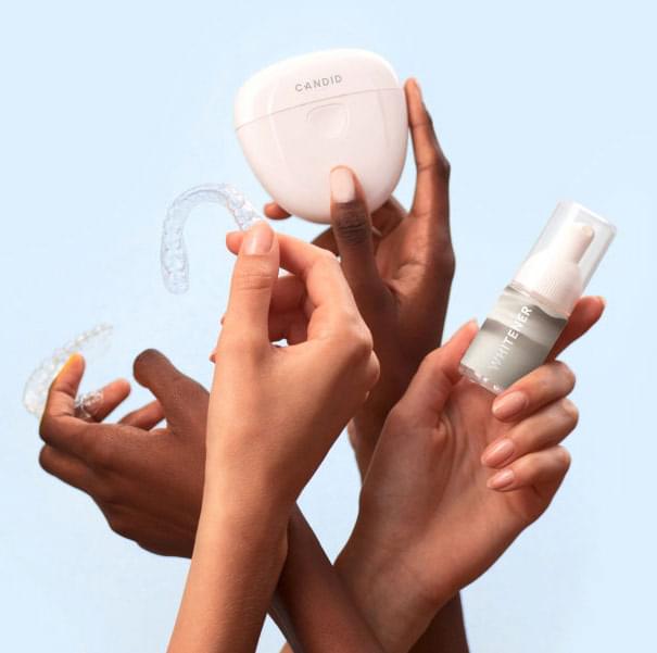 hands holding invisible aligners , whitener and a box