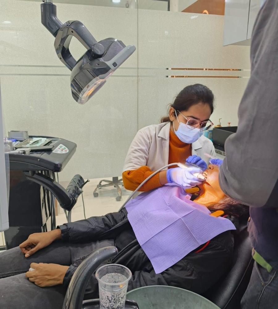 Dr. Shalini Singh performing dental treatment Dr. Shalini Singh is performing a dental procedure for a woman patient with a male nurse nearby assisting her in the Thanks Dental and Aesthetics clinic.