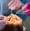 Closeup of a scaling and polishing procedure performed by two dentists in pink gloves to a male client.